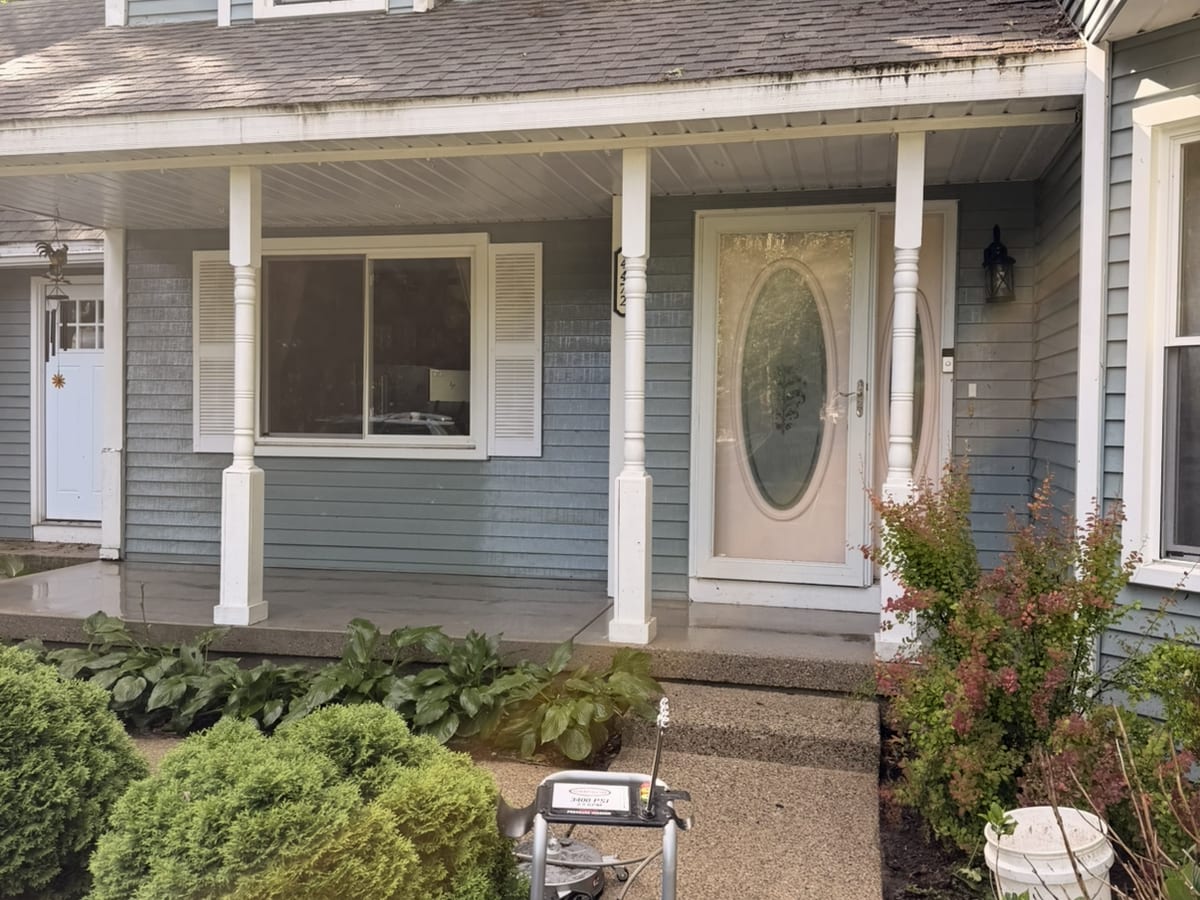 Clean front porch with bright white columns and freshly washed siding after exterior cleaning